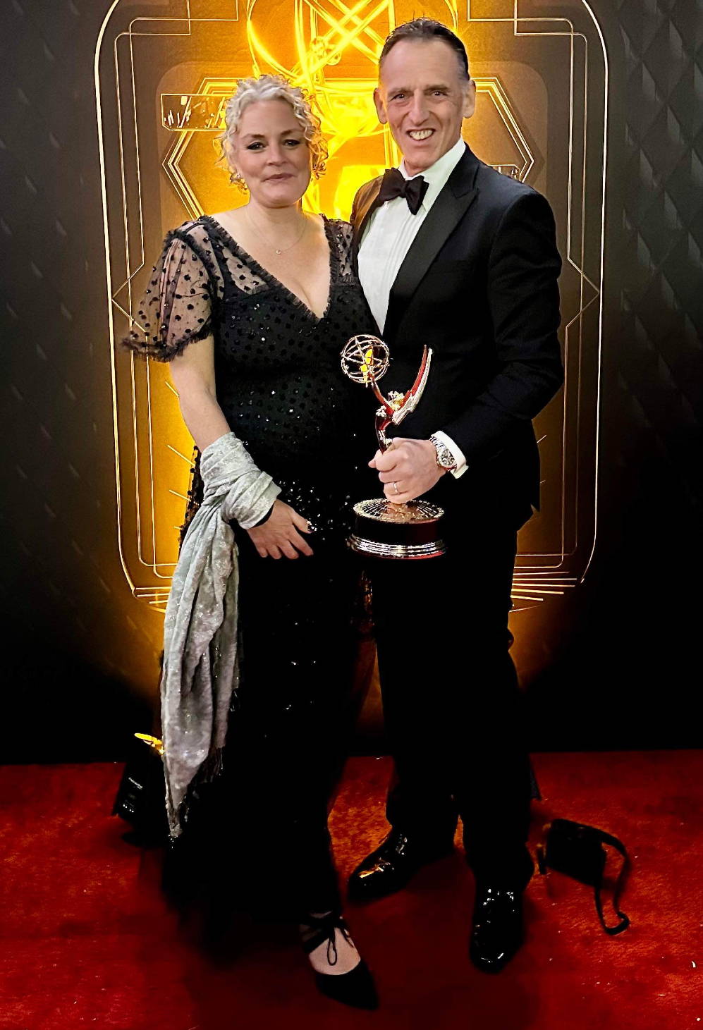 Photo of a man and woman at an awards ceremony, with the woman wearing Sargasso & Grey shoes