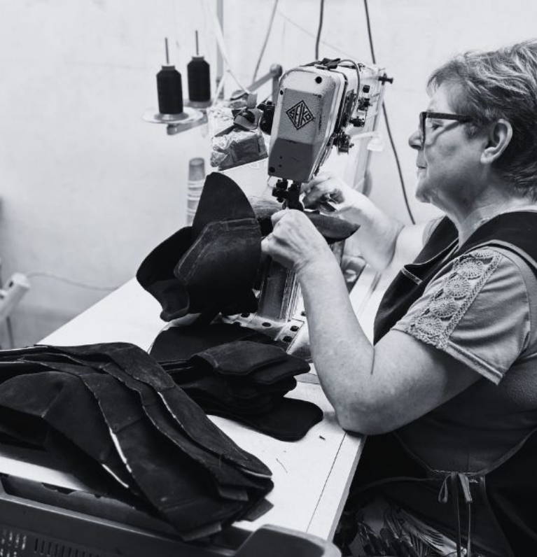 Person working with leather at a sewing machine in a workshop.