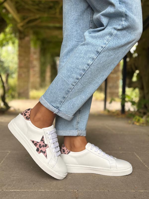 White sneakers with leopard print accents worn with light blue jeans outdoors.